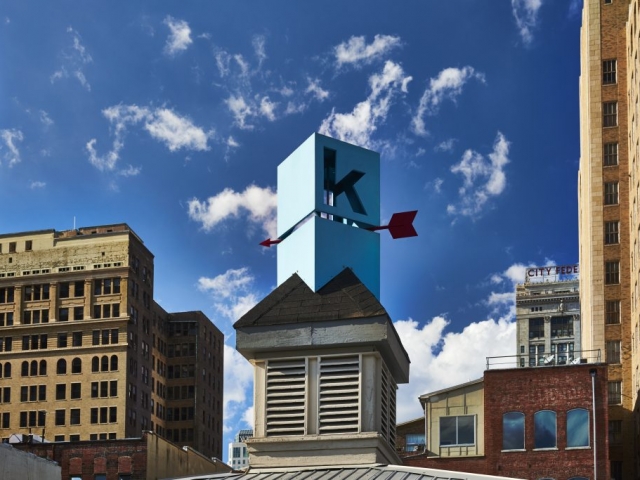 Photo of Kinetic's weathervane logo on top of the building during daylight.